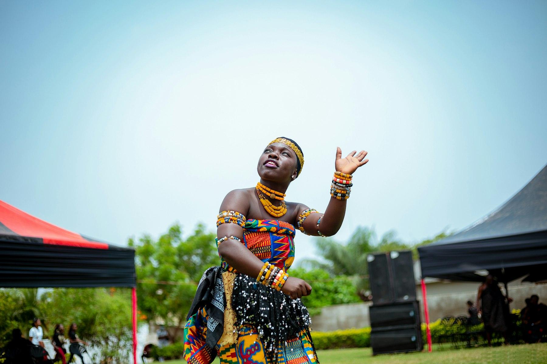 A dancer in kente and beads performing at a Ghanaian cultural festival